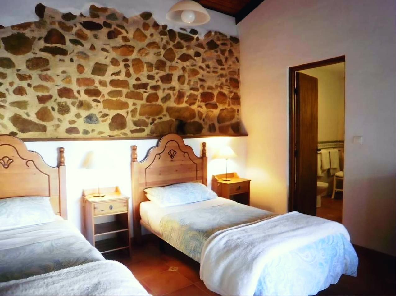 Guest bedroom with stone wall and timber headboards